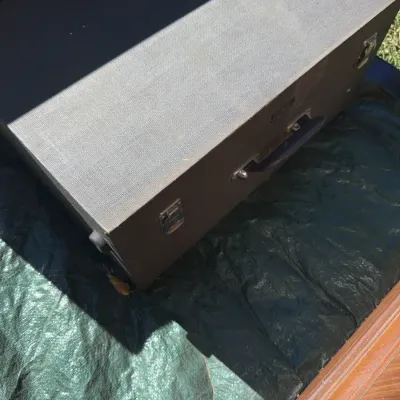Sale Photo Thumbnail #71: Vintage portable record player or audio equipment case with a textured gray vinyl exterior, carrying handle, and metal latch closures.