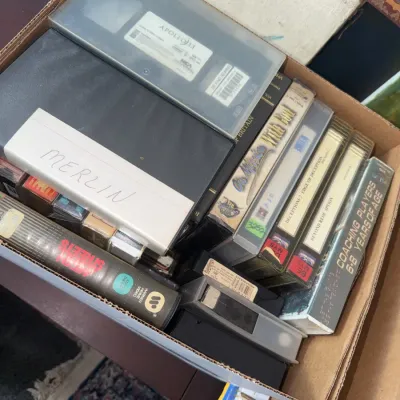 Sale Photo Thumbnail #177: Cardboard box filled with vintage VHS tapes, including titles such as Apollo 13, Mean Streets, and instructional sports videos.