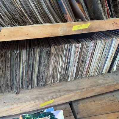 Sale Photo Thumbnail #81: Large collection of vintage vinyl LP records stacked vertically on wooden shelving units.