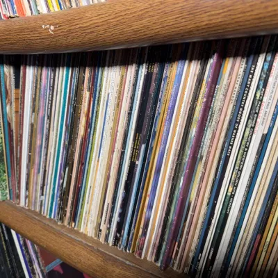 Sale Photo Thumbnail #106: Large collection of vintage vinyl LP records stacked vertically on wooden shelf units.