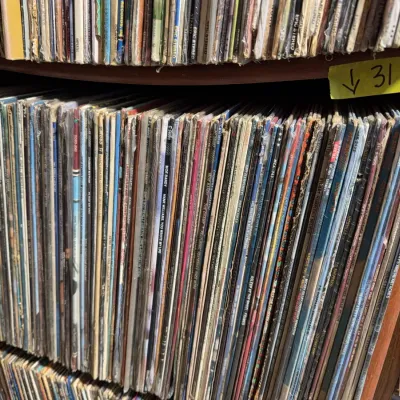 Sale Photo Thumbnail #113: Large collection of vintage vinyl LP records stacked vertically on wooden shelving.