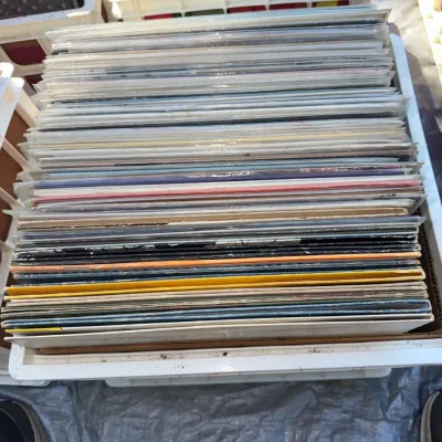 Sale Photo Thumbnail #31: A plastic crate filled with sleeved vinyl LP records, stacked tightly together for browsing.