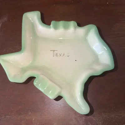 Sale Photo Thumbnail #185: Vintage Texas-shaped ceramic souvenir ashtray with light green painted trim and handwritten "Texas" text in the center.