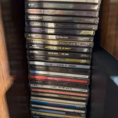 Sale Photo Thumbnail #168: Vertical stack of assorted music audio CDs in jewel cases, including titles from EMF, Ace of Base, and Possum Dixon, circa 1990s to 2000s.