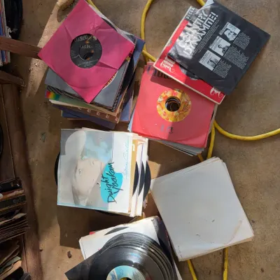 Sale Photo Thumbnail #102: Collection of vintage 45 RPM vinyl records and picture sleeves arranged in stacks on the floor.
