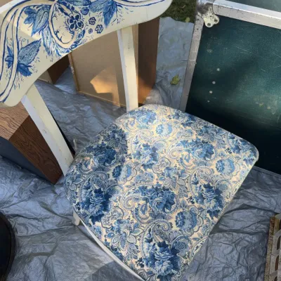 Sale Photo Thumbnail #42: Hand-painted wooden dining chair with blue floral motifs on a cream crest rail and matching blue paisley fabric upholstery.