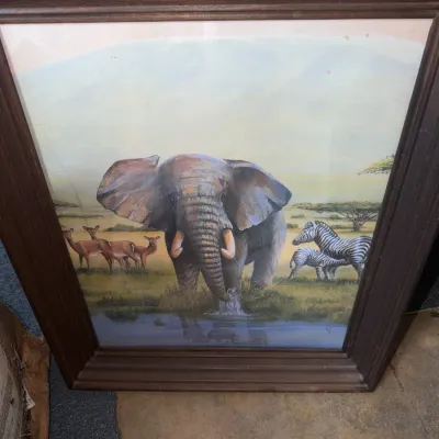 Sale Photo Thumbnail #175: Framed African safari wildlife art print featuring an elephant, zebras, and impalas by a watering hole, set in a dark molded wooden frame.