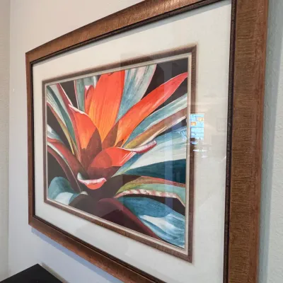 Large framed botanical art print depicting a vibrant bromeliad in shades of orange, red, and blue. Housed in a substantial textured wood...