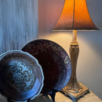 Traditional buffet table lamp paired with two decorative painted display plates resting on stands.