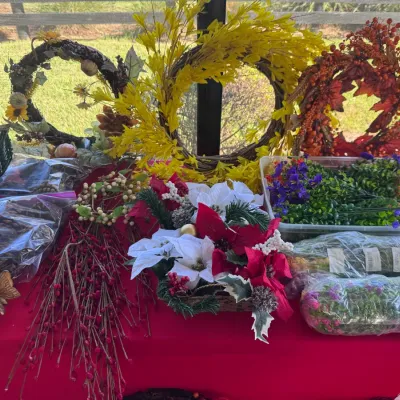 Collection of seasonal floral decor, including various faux wreaths, poinsettia arrangements, decorative berries, and packaged artificial...