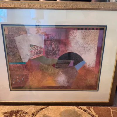 Sale Photo Thumbnail #113: Large framed abstract artwork in rich burgundy, beige, and geometric tones, presented behind glass with a textured gold-finished frame.