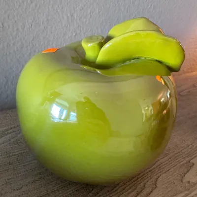 Glossy lime green ceramic apple sculpture featuring a short stem and detailed leaves.