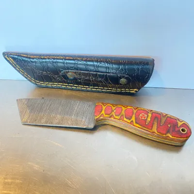 Sale Photo Thumbnail #78: Custom Damascus steel cleaver-style fixed blade knife featuring a red and yellow laminated wood handle and a black faux-croc leather sheath.