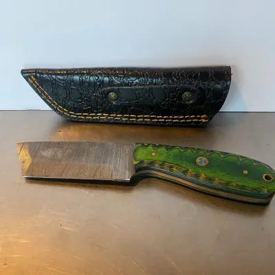 Sale Photo Thumbnail #95: Custom fixed-blade Damascus steel knife featuring a textured green laminate handle with mosaic pin accents, accompanied by a black alligator-embossed leather sheath.