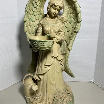 Sale Photo Thumbnail #31: Cast resin garden angel statue with subtle green wash finish, featuring a bird perched on a woven basket bowl and a watering can at the base.