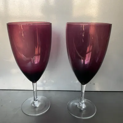 Sale Photo Thumbnail #39: Pair of vintage amethyst purple wine glasses featuring clear glass stems and circular bases.