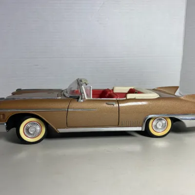 Sale Photo Thumbnail #36: Vintage 1/18 scale die-cast model 1959 Cadillac Eldorado convertible in metallic gold with red interior and whitewall tires.