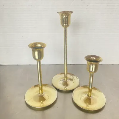 Sale Photo Thumbnail #3: Trio of vintage brass candlestick holders in varied heights, showing moderate surface wear and patina.