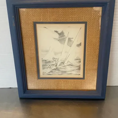 Sale Photo Thumbnail #22: Framed black and white nautical sketch depicting sailboats on choppy waters, presented with a burlap mat and a navy blue wooden frame.