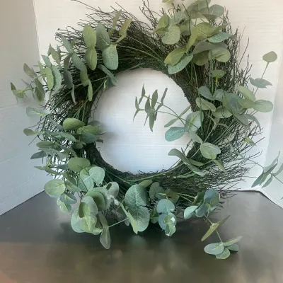 Sale Photo Thumbnail #14: Rustic decorative wreath featuring a twig base interspersed with faux eucalyptus foliage.