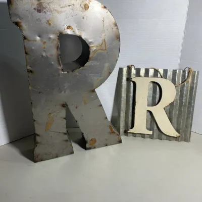 Sale Photo Thumbnail #111: Two decorative metal signs featuring the letter 'R', including a large freestanding industrial metal letter and a small hanging corrugated metal plaque with a painted wooden 'R'.