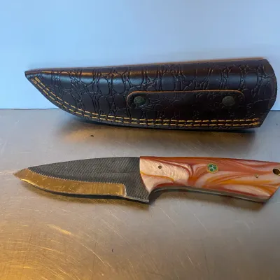 Sale Photo Thumbnail #59: Custom fixed-blade knife crafted from a steel file, featuring a swirling orange and white acrylic handle with mosaic pins and a fitted brown textured leather sheath.