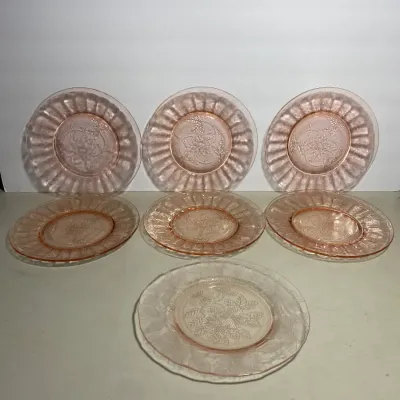 Sale Photo Thumbnail #28: Set of seven vintage pink Depression glass plates with embossed floral and scalloped rim designs.