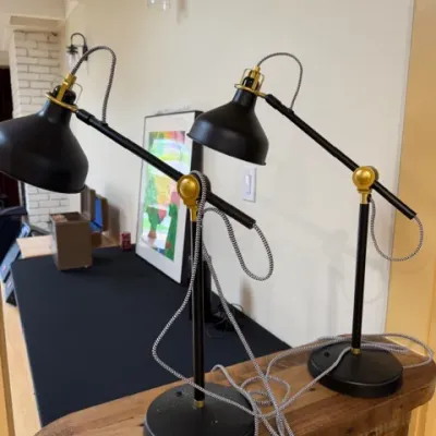 Sale Photo Thumbnail #85: Pair of modern industrial-style adjustable desk lamps featuring matte black metal shades and bases with brass accents and braided cords.