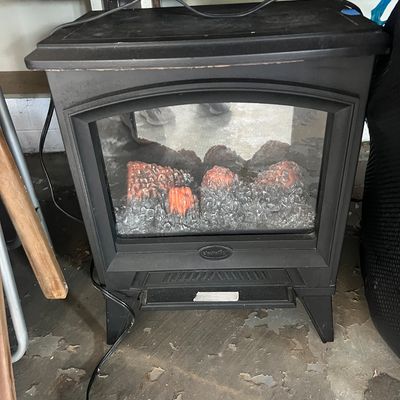 Sale Photo Thumbnail #8: Compact black electric fireplace heater, featuring a faux log display and glass view panel.