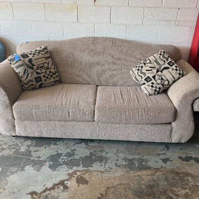 Sale Photo Thumbnail #2: Beige textured upholstery sofa featuring rolled arms and paired with two geometric patterned throw pillows.