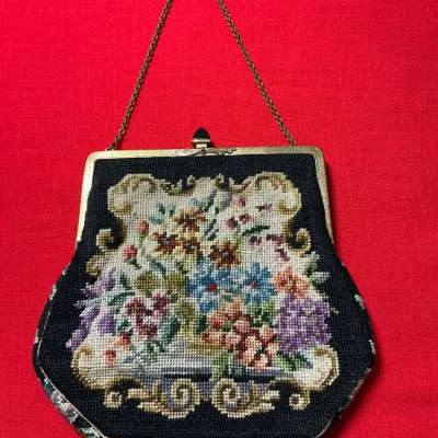 Vintage embroidered needlepoint handbag featuring a colorful floral motif, gold-tone kiss-lock frame, and thin chain strap.