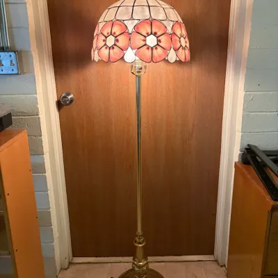 Vintage brass floor lamp featuring a Tiffany-style leaded glass shade with pink floral panels and scalloped edges.