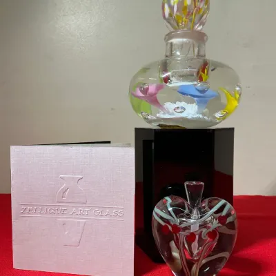 Pair of Zellique Art Glass perfume bottles featuring a floral paperweight design with stopper and a heart-shaped bottle, displayed with...