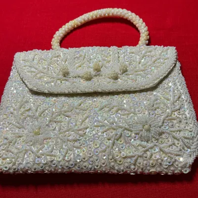 Vintage white beaded and sequined evening handbag featuring an intricate floral pattern and a beaded top handle.