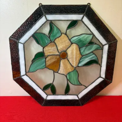 Octagonal stained glass suncatcher panel featuring a central yellow flower with green leaves and a dark brown border, equipped with top...