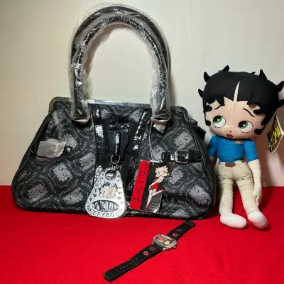 Betty Boop collectibles set including a black printed shoulder bag with tags, a plush doll with original tags, and a wristwatch.