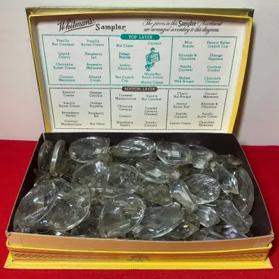 Vintage Whitman's Sampler chocolate box filled with assortment of faceted clear glass chandelier prisms.