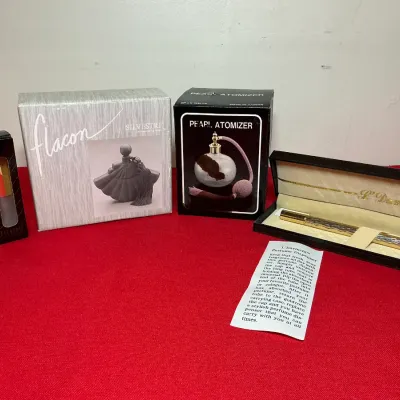 Collection of vintage perfume bottles and dispensers in original packaging, including a Silvestri Flacon, Pearl Atomizer, and...
