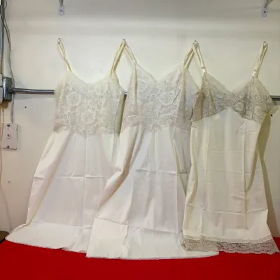 Set of three vintage ivory full slips featuring lace bodices and adjustable shoulder straps.