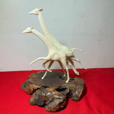 John Perry studio sculpture featuring two running giraffes crafted in pellucida resin mounted on a natural burl wood base.