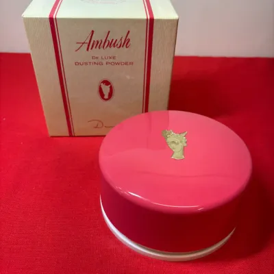Vintage Ambush by Dana deluxe dusting powder container with original box, featuring a bright pink case with gold-tone cameo emblem.