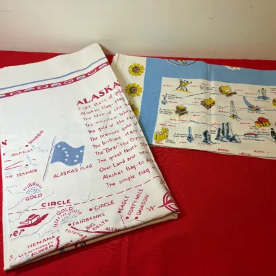 Pair of vintage souvenir linen tea towels featuring printed map graphics of Alaska and Kansas.