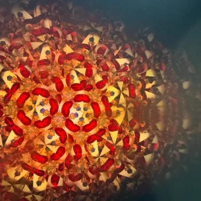 Interior kaleidoscope view featuring a geometric pattern composed of vibrant red glass pieces and gold reflective panels.