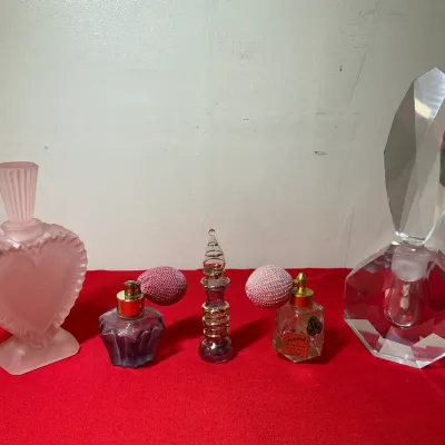 Collection of five vintage decorative glass perfume bottles, including a frosted pink heart-shaped bottle, two atomizer bottles, a...