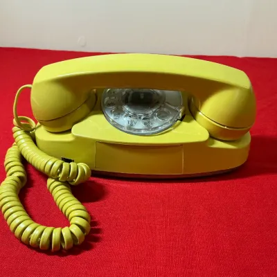 Vintage chartreuse yellow Western Electric Model 500 rotary desk phone with coiled cord.