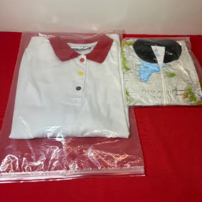 Two packaged vintage shirts including a Marcy 'n Me polo with a red collar and colorful buttons alongside a map-print shirt.