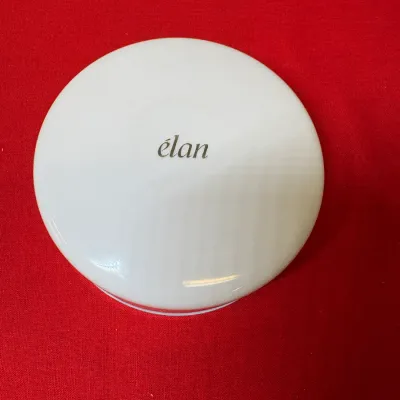 Vintage Coty Élan white plastic powder compact, featuring gold script branding on the lid.