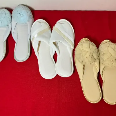 Three pairs of vintage women's house slippers, including two pairs embellished with fabric rosette pom-poms and one pair with cream...