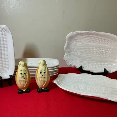 Vintage ceramic corn-on-the-cob serving set featuring white embossed corn dishes and a pair of happy and sad anthropomorphic corn salt...