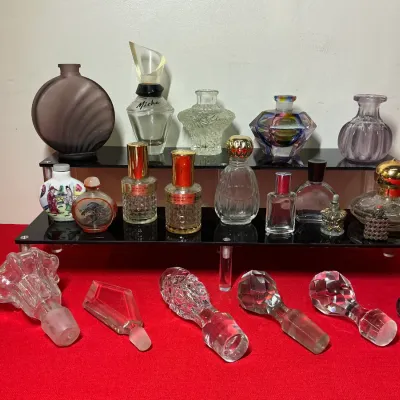 Collection of vintage decorative perfume bottles, snuff bottles, and glass stoppers displayed on a two-tier acrylic stand.
